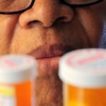 Senior man closely examining two prescription pill bottles
