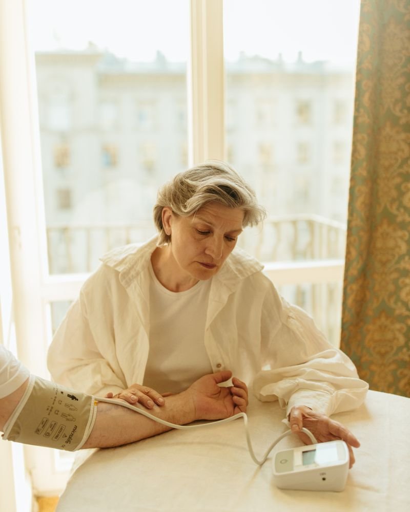 Senior woman monitoring her blood pressure at home by a sunlit window