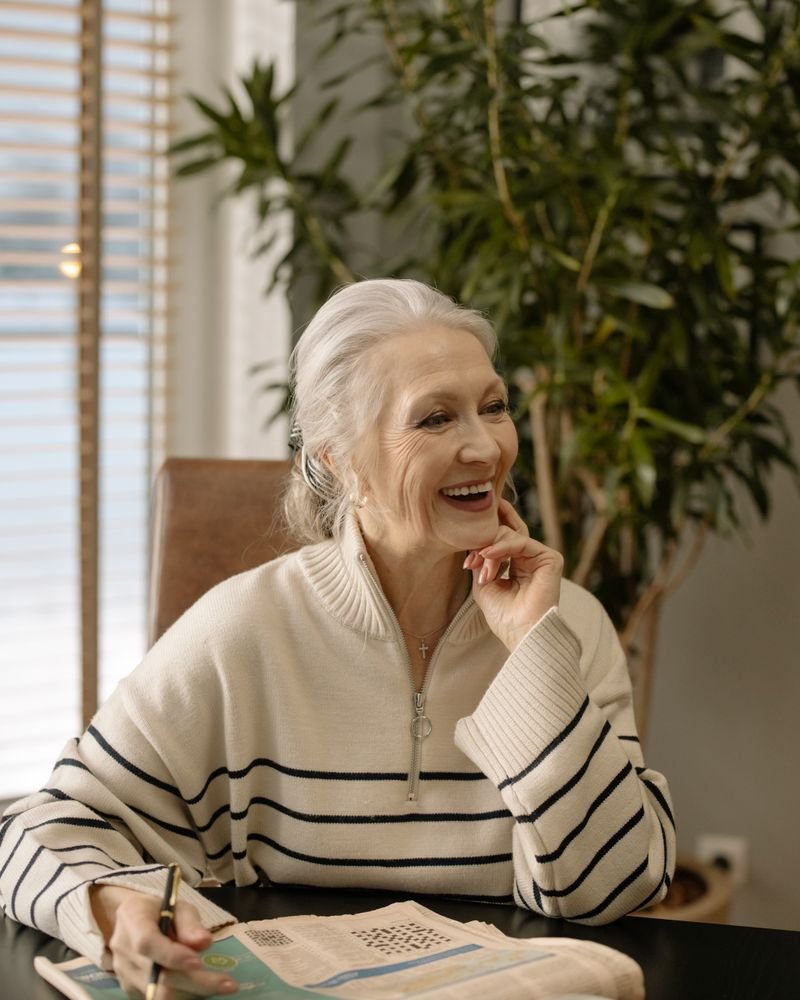 Smiling senior woman doing a crossword puzzle at home, engaged in a mentally stimulating activity