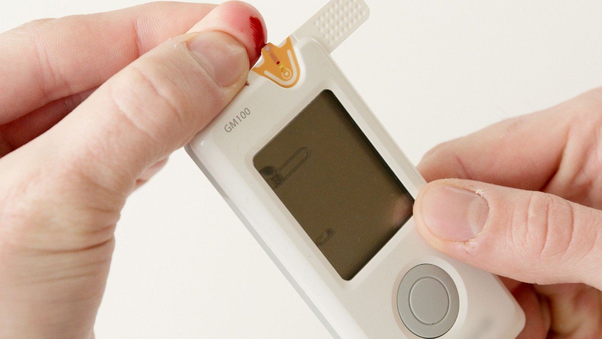 Close-up of hands using a glucometer to check blood sugar levels