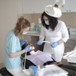 Dentists in medical masks examining a patient's teeth in a modern dental clinic