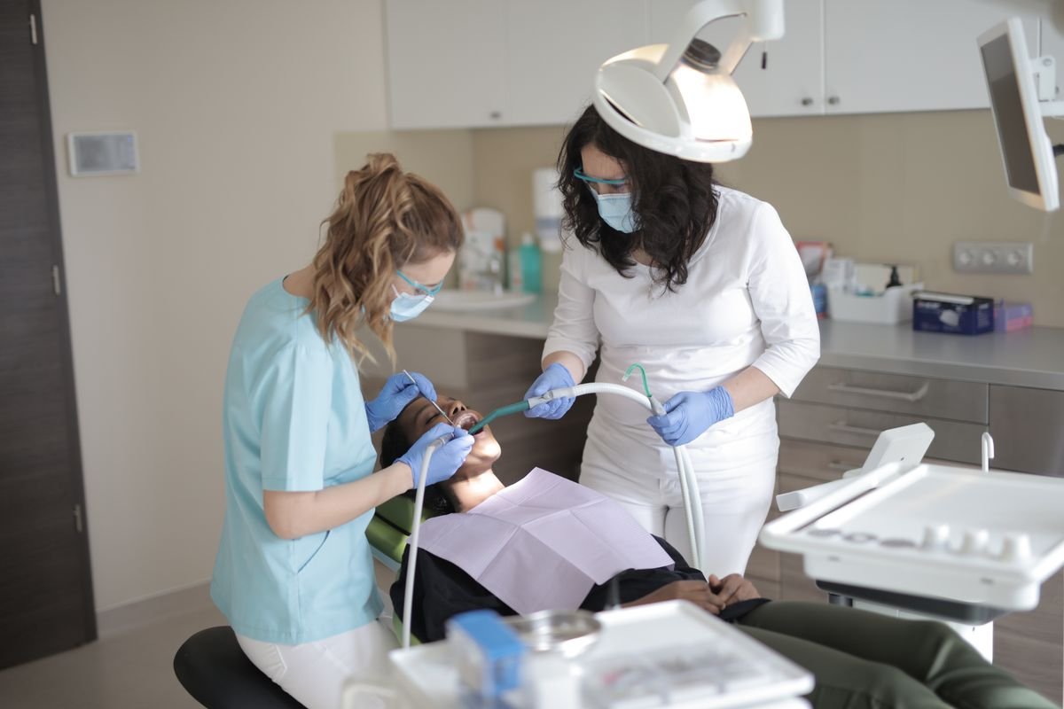 Dentists in medical masks examining a patient's teeth in a modern dental clinic