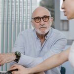 Elderly man in a consultation with a healthcare provider, discussing his medication at a desk
