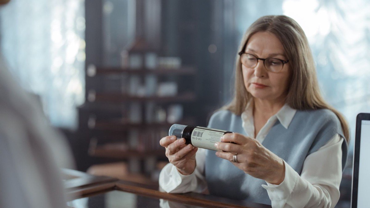 An older adult reading a supplement label closely before buying a joint supplement
