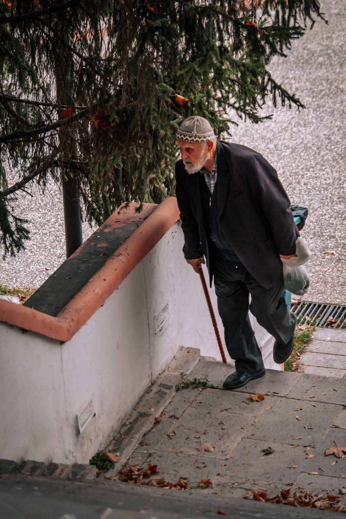 Elderly man using a cane while navigating stairs due to knee pain