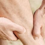 Close-up of a person clutching their calf muscle in pain