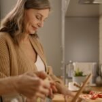 Elderly woman preparing a healthy, vegetable-forward meal in a bright kitchen
