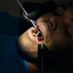Dentist performing a close dental examination with a mouth mirror and probe