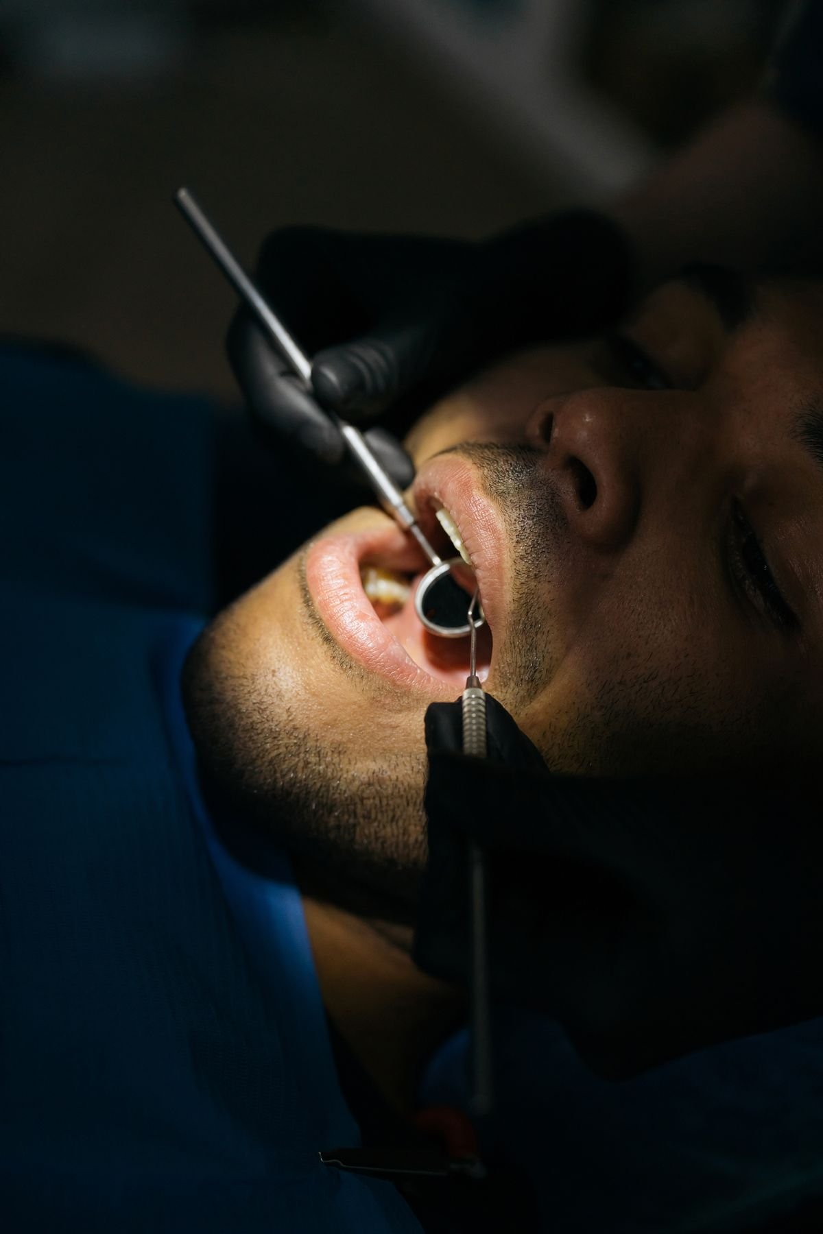Dentist performing a close dental examination with a mouth mirror and probe