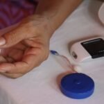 Close-up of hands using a glucometer to check blood sugar at home