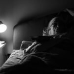 Senior woman lying awake in bed at night under a lamp