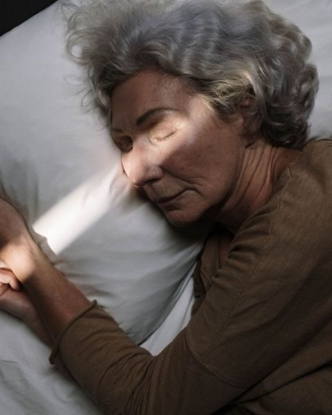 Senior woman sleeping peacefully in bed with soft morning light