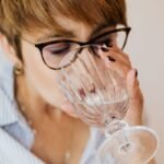 Woman with eyes closed drinking a glass of water