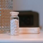 Close-up of a glass of water and a bottle of sleep medication on a bedside nightstand