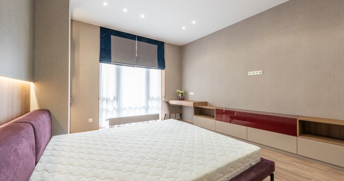 Clean bedroom with a bare mattress on a bed frame, the kind of spot where bed bugs commonly hide.