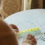 Senior man with glasses sorting medication into a weekly pill organizer
