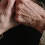 Close-up of an adult's hands gently holding an older adult's hands