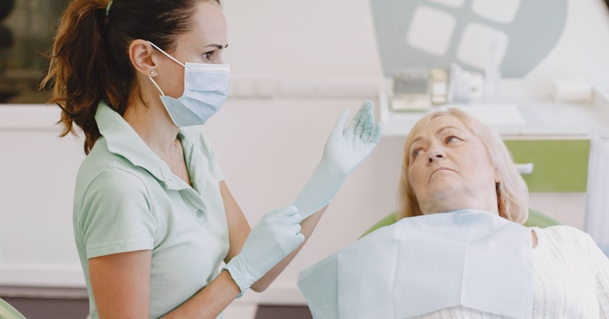 Dentist putting on gloves while consulting with a senior patient