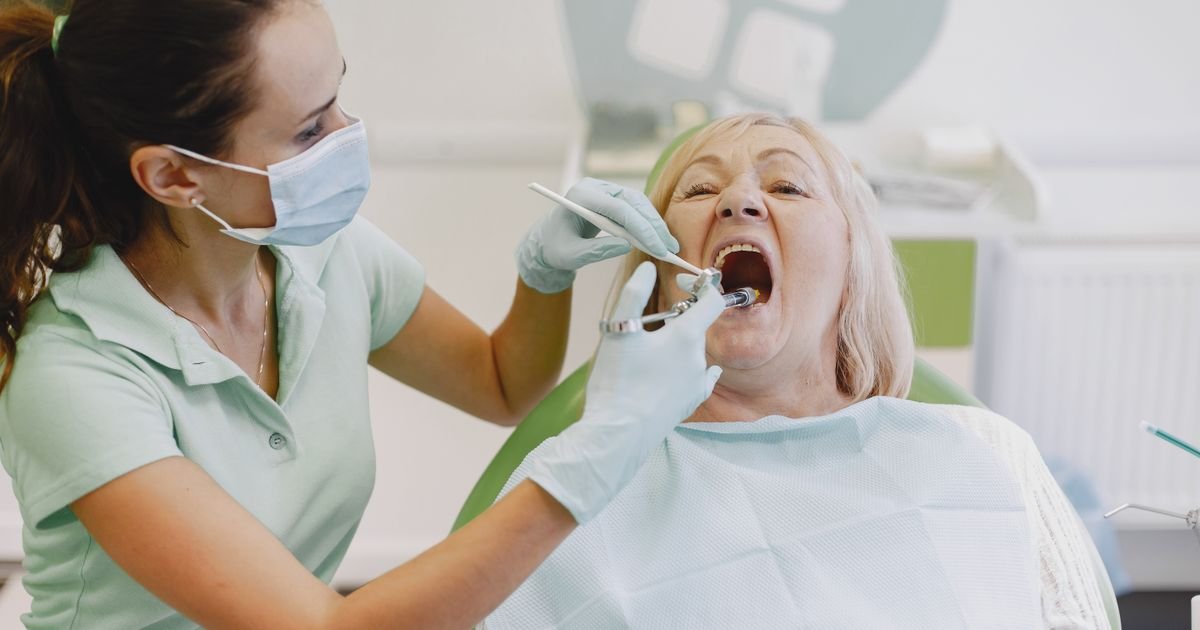 Dentist examining an older female patient in a dental chair