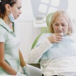 A dentist assisting a senior patient rinsing her mouth during a dental visit