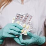 A healthcare professional in gloves holding blister packs of prescription medication