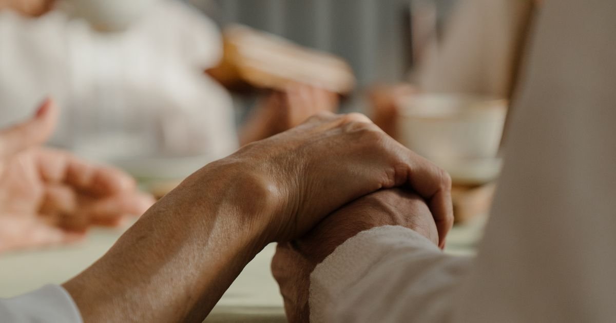 Elderly couple holding hands warmly during a family gathering