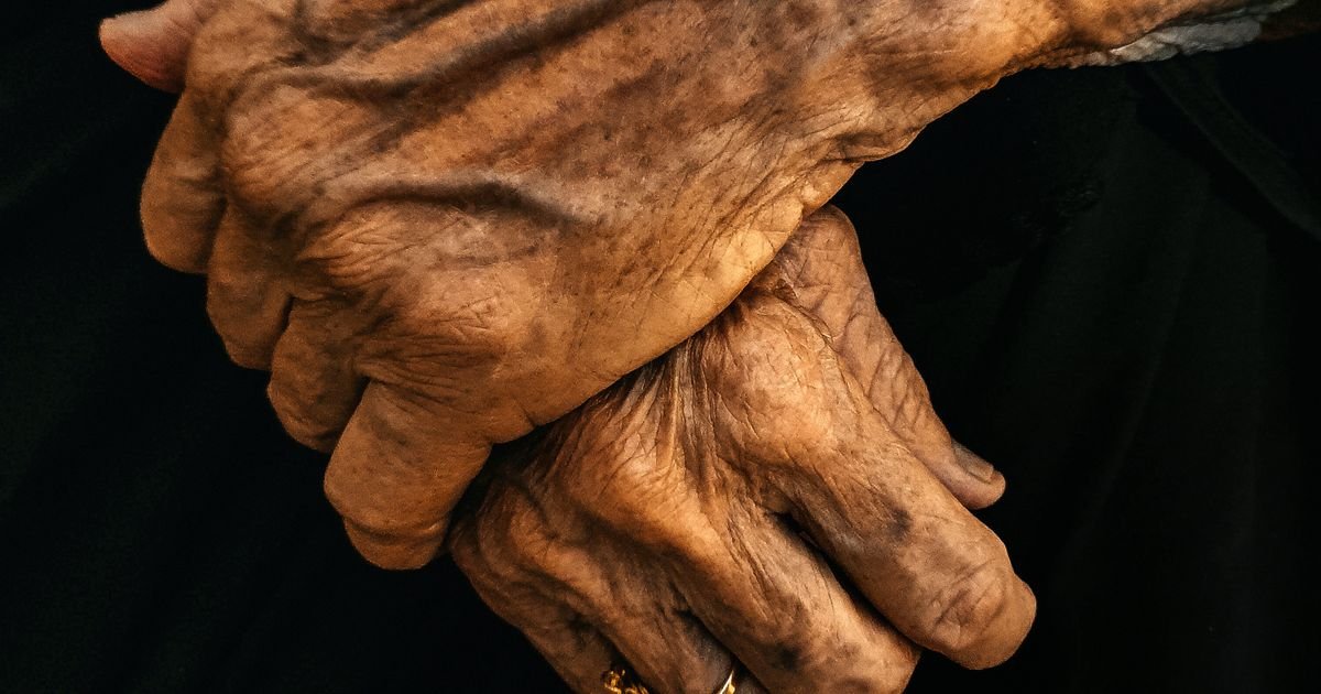 Older adult's hands checking a blood glucose meter at a wooden table