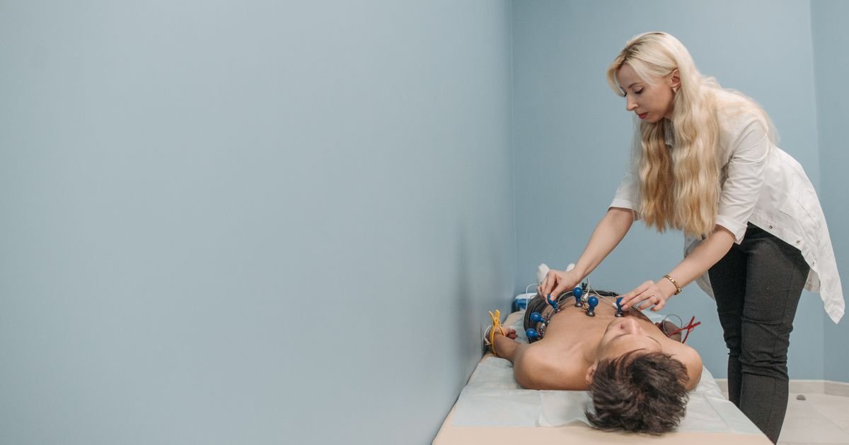 Healthcare professional performing an electrocardiogram on a patient in a clinic.