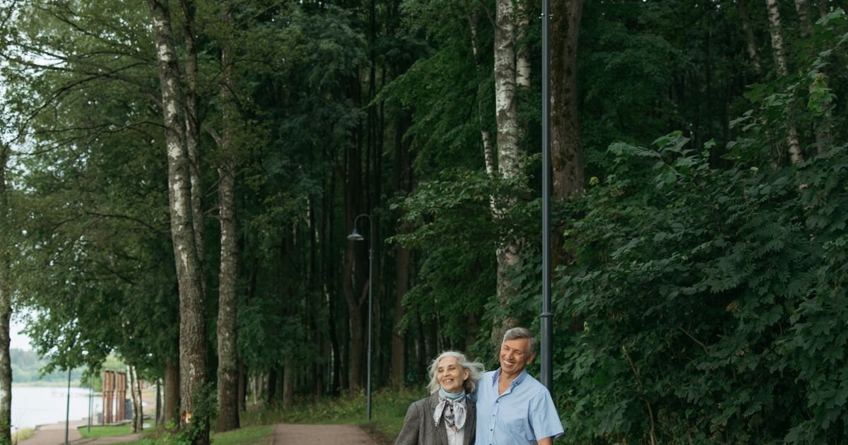 Senior couple walking together outdoors on a tree-lined path