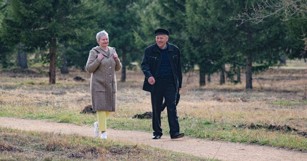 Happy senior couple walking together along a park path on a sunny day