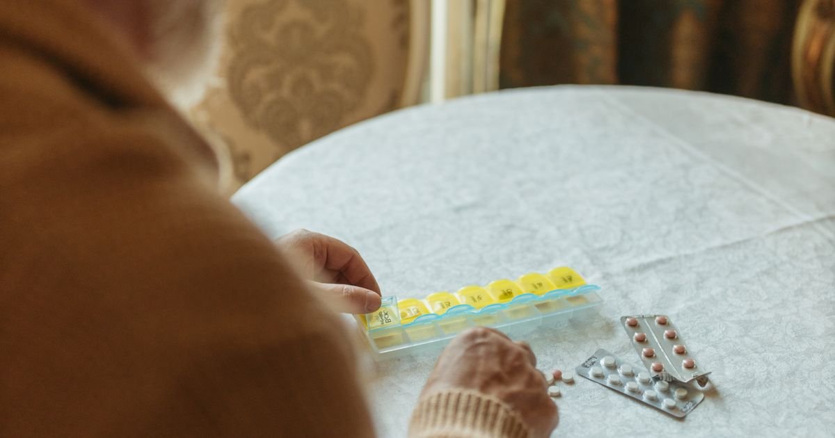 Senior man sorting his daily medication into a pill organizer at home