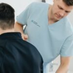 Physiotherapist examining a patient's lower back in a clinic setting