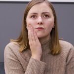 Woman holding her cheek in discomfort in a dental clinic setting