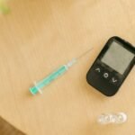 Glucometer and syringe resting on a wooden table, used for diabetes management