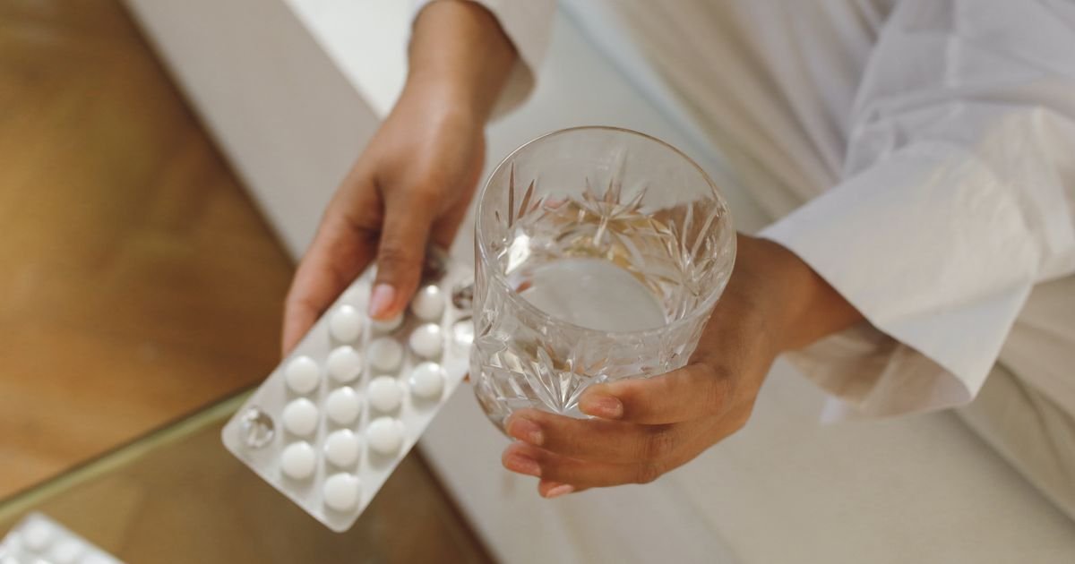 Close-up of hands holding pills and a glass of water