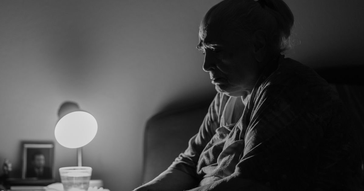 Older woman sitting awake in bed at night, unable to sleep